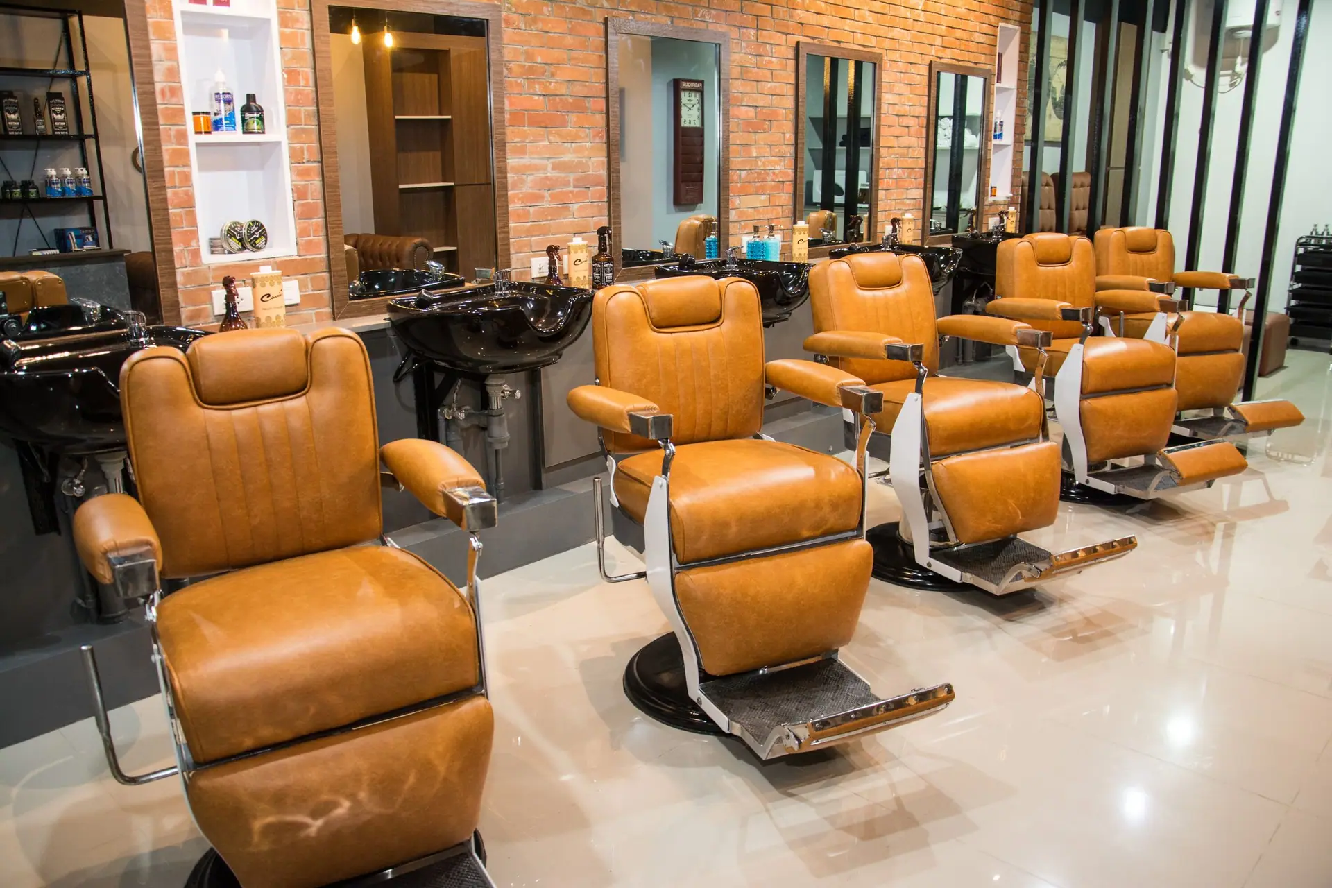 Lyst barbershop med brune skinnstoler og speil